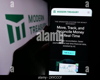 Person, die ein Handy hält, mit Webseite der US-Geldbewegung Modern Treasury Corp. Vor dem Logo. Konzentrieren Sie sich auf die Mitte des Telefondisplays. Stockfoto