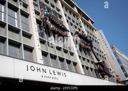 Bauunternehmer, die Seile und Gurte verwenden, um am 28. August 2024 in London ein Design an der Außenfassade des Kaufhauses John Lewis in der Oxford Street zu kleiden. Stockfoto