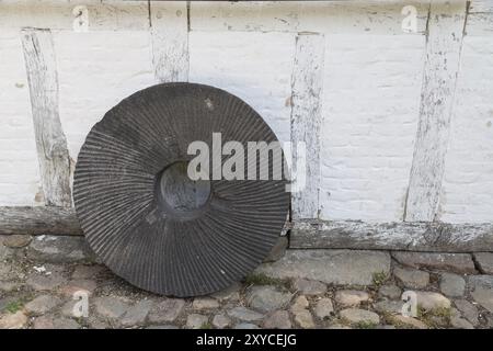 Ein alter Mühlstein, der auf einer Mauer steht Stockfoto