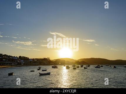 Fischerboote am Meer und Bauten, die das Meer bei Sonnenuntergang in der Stadt Buzios im Sommer Stockfoto