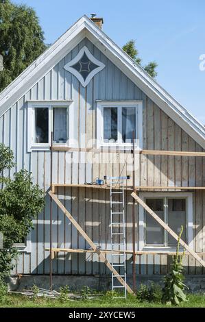 Haus auf der Insel Oeland, Schweden, vorbereitet für einen neuen Anstrich. Gerüst vor dem Giebel, der alte Lack wurde bereits entfernt Stockfoto