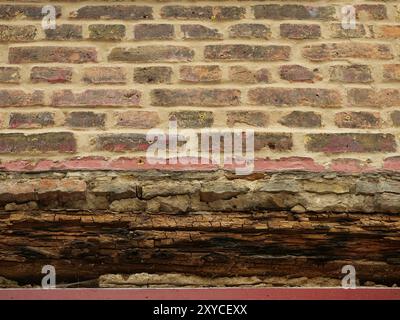 Freiliegendes Mauerwerk mit verrottetem Holzsturz über einer Fensteröffnung während der Renovierung. Ideal als Textur oder Hintergrund für kreative Projekte. Stockfoto