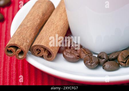 Kaffeetasse mit Zimt, Kaffeekörnern und einem Löffel an der Seite Stockfoto