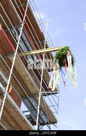 Ein Kränz, der an einem Gerüst befestigt ist. Krönung der Dachzeremonie auf einem Gerüst Stockfoto
