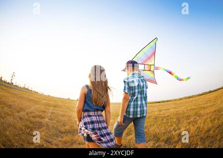 Glückliche kleine Kinder spielen mit Drachen auf der Sommerwiese Stockfoto