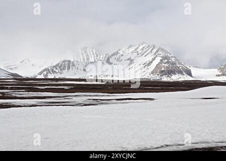 Schneebedeckte Berge an einem nebeligen Tag in NY Alesund, Svalbard Inseln, Norwegen, Europa Stockfoto