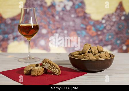 Italienische cantucci Kekse über einen roten Serviette und ein Glas vin santo Wein auf Hintergrund Stockfoto