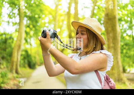 Nahaufnahme einer kaukasischen jungen, fröhlichen Frau, die mit der Kamera durch den Wald wandert Stockfoto