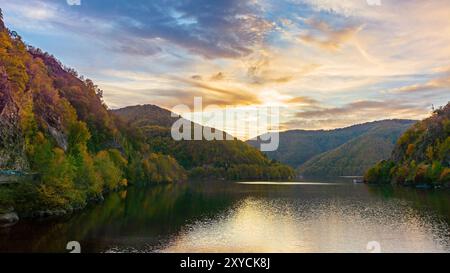 see in den Bergen an einem sonnigen Abend. Wald reflektiert sich im Wasser. Wunderschöne Landschaft rumäniens in der Herbstsaison. Malerische Wolkenlandschaft Stockfoto