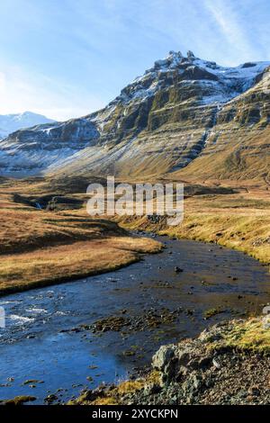 Eine Bergkette mit einem Fluss, der durch sie fließt. Der Fluss ist blau und die Berge sind mit Schnee bedeckt. Die Szene ist friedlich und ruhig Stockfoto