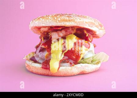 Hamburger, mit geschmolzenem Käse, Zwiebeln, Paprika, Speck, Ketchup, Senf, scharfer gemahlener Pfeffer, asturisches Rindfleisch, Spanien. Rosafarbener Hintergrund Stockfoto