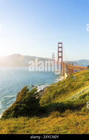 Das Sonnenlicht bietet wichtige Highlights über den Marin Headlands mit der Golden Gate Bridge, die während des Sonnenuntergangs in San Franci über der felsigen Küste von Fort Point zu sehen ist Stockfoto