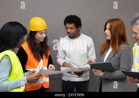 Verschiedene Teams von Architekten und Bauarbeitern arbeiten an einem Projekt zusammen, prüfen Baupläne und diskutieren Pläne Stockfoto
