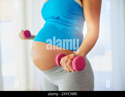 Kurzhantel, schwangere Frau und Magen zu Hause mit Fitness für pränatale Bewegung, starke Muskeln und Wellness. Workout, Person und Bauch mit Stockfoto