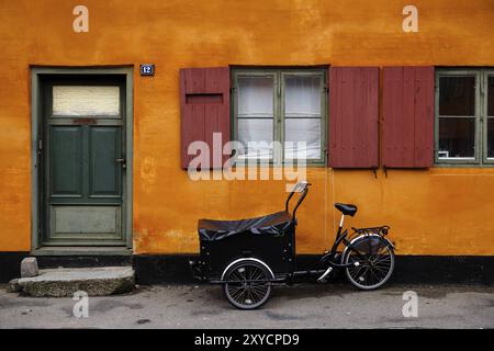 Kopenhagen, Dänemark, 01. März 2014: Foto eines traditionellen dänischen Dreirads vor einem orangen Haus in Europa Stockfoto