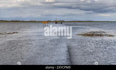 In der Nähe von Beal, Northumberland, England, Großbritannien, 08. September 2018: überflutete Straße zur Heiligen Insel Lindisfarne mit einem Wagen Stockfoto