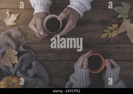 Verliebtes Paar holding Tasse Tee oder Kaffee am Tisch mit Herbstlaub bedeckt Stockfoto