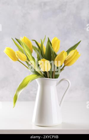 Blumenstrauß aus gelben Tulpen in einem Krug auf grauem Steinhintergrund Draufsicht, flacher Laienkopierraum Stockfoto