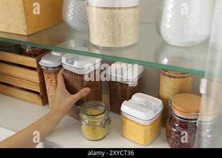 Frau mit Behältern mit verschiedenen Getreide und Hülsenfrüchten in der Küche, Nahaufnahme Stockfoto