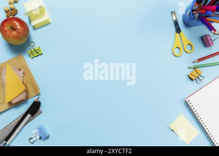 Flat Lay mit Schul-, Arbeits- oder Kreativitätskonzept mit verschiedenen Schulzubehör, Stiften, Bleistift, Notizblock, Büroklammern, apfel, Nüsse, Sandwich, Lineal, Stockfoto