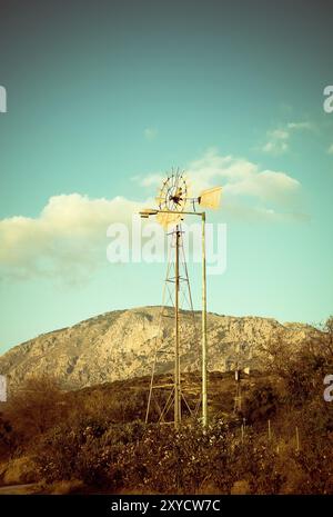 Schöne Retro-Landschaft mit Windmühle und Bergen gegen blauen Himmel mit weißen Wolken auf der Landschaft Stockfoto