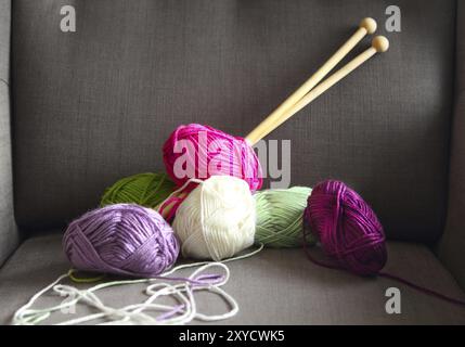 Bunte Kugeln aus Garn auf dem grauen Sessel. Nahaufnahme Stockfoto