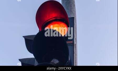 Nahaufnahme einer roten Ampel vor klarem Himmel, die Fahrzeuge zum Anhalten signalisiert und die Straßensicherheit gewährleistet. Rote Leuchte, Stopp. Stockfoto