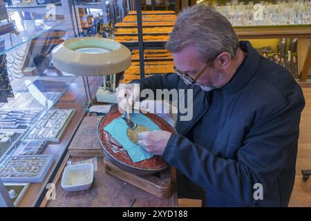 Ein älterer Mann graviert ein detailliertes Muster auf eine Metallplatte in einer gut ausgestatteten Werkstatt in Toledo, Castilla-La Mancha, Spanien, Europa Stockfoto