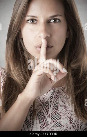 Nahaufnahme einer Frau mit dem Finger vor den Mund, in eine düstere Stimmung Stockfoto