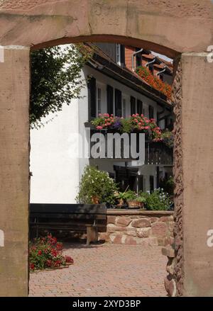 Alter Torbogen vor einem Gebäude mit bunten Blumen in Dilsberg, einer historischen Stadt in der Nähe von Heidelberg, Deutschland, Europa Stockfoto