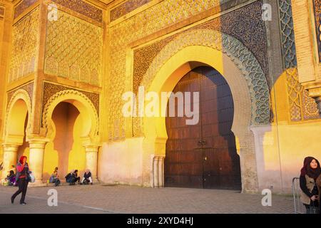 Meknes, Marokko, 4. April 2018: Marokkaner vor dem historischen Tor von Bab Al-Mansour während der goldenen Stunde am späten Nachmittag. Horizontal, Afrika Stockfoto