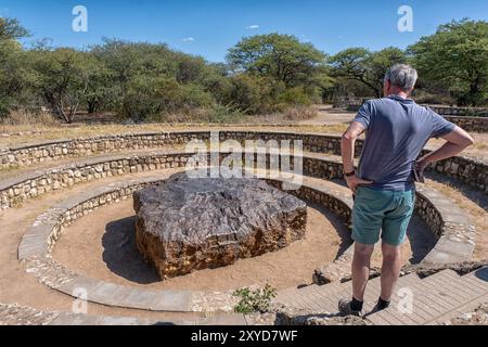 Ein Mann, der den Hoba-Meteoriten in Namibia ansieht. Er wiegt 66 Tonnen, ist der größte jemals gefundene Meteorit der Welt und wurde nie von dort entfernt Stockfoto