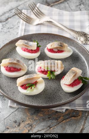 Nahaufnahme teuflischer Eier mit Rote-Bete-Salat und Hering auf einem Teller auf dem Tisch. Vertikal Stockfoto