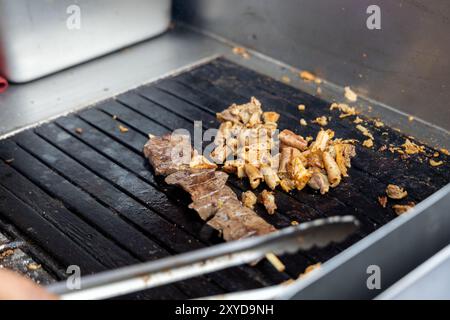 Eine Person kocht Antikuchos auf einem Grill. Das Fleisch wird auf Spießen gekocht und wird von anderem Fleisch umgeben Stockfoto