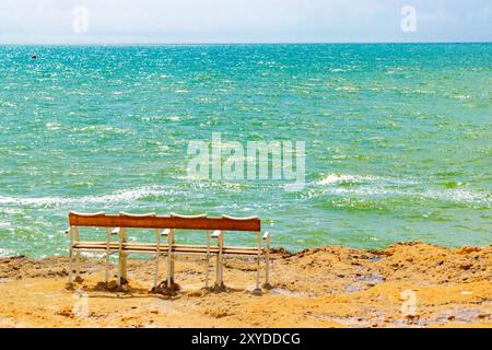 Leere 4-Sitzbank mit Blick auf das riesige, türkisfarbene Meer an einem klaren Tag von einem Sandstrand. Portugal Stockfoto