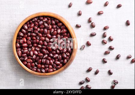 Adzuki-Bohnen in einer Holzschale auf Leinenstoff. Auch bekannt als Azuki, Aduki, rote oder rote Mungbohne. Getrocknete Samen von Vigna angularis. Stockfoto