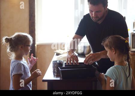 Vater und seine zwei kleinen Helfer. Kinder kochen hausgemachtes Brot mit es Vater Stockfoto