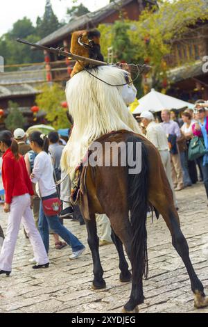 Lijiang, China, 30. September 2017: Ein Hinterteil eines Naxi ethnischen Minderheitenmannes, gekleidet in traditioneller Kleidung, Pelz, auf einem Platz in der Altstadt von Lij Stockfoto