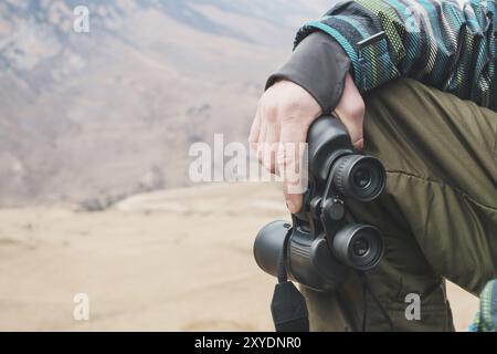 Großes Fernglas in der Hand eines Reisenden, der in den Bergen ist, aus nächster Nähe Stockfoto