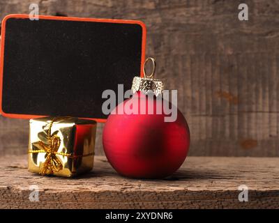 Kleine chalkboartd mit einem alten Weihnachtskugel und Geschenk Box auf einem rustikalen Holzmöbeln Hintergrund Stockfoto