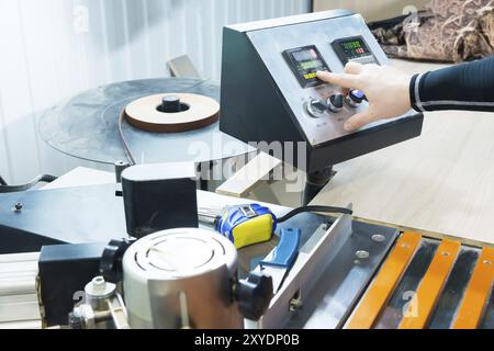 Eine Nahaufnahme des Bedieners der Mann drückt die Taste auf dem Bedienfeld mit den Steuergeräten der Möbelproduktion. Die handpresse des Mannes Stockfoto