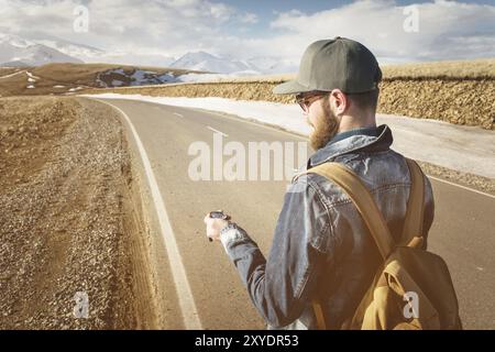 Hipster-Mann mit einem Kompass auf einem verschneiten Berg Stockfoto