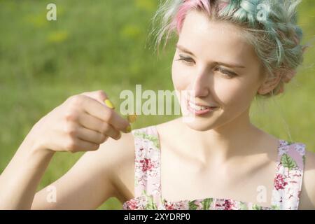 Porträt einer schönen Frau, die einen Schmetterling auf der Hand im Garten hält. Schönheitsporträt. Einheit mit der Natur. Ökologie Konzept Stockfoto