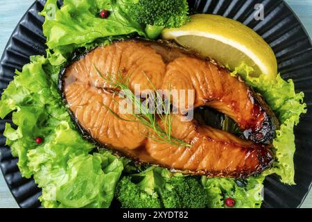 Gebratenes Lachssteak mit Gier Salatblättern und Zitrone, Overhead Nahaufnahme Stockfoto