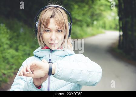 Porträt Junge Fitness-Frau, die ihre Smartwatch ansieht, während sie eine Pause vom Sporttraining macht. Sportsfrau überprüft Puls auf Fitness-Smartwatch d Stockfoto