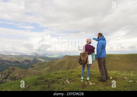 Ein junges Paar Touristen auf der Natur in den Bergen zeigen ihre Hände in Richtung der Berge. Das Konzept des einfachen Tourismus Stockfoto