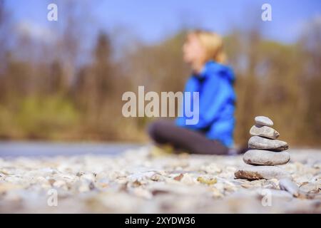 Auf einem Kieselstrand Cairn, meditieren, Frau im Hintergrund Stockfoto