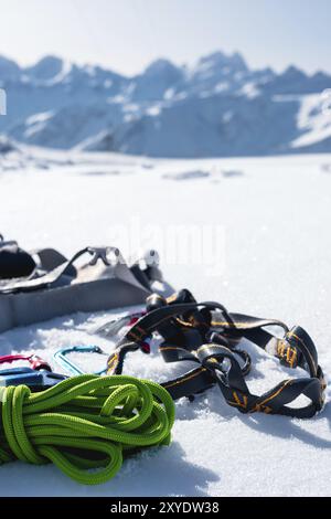 Winterausrüstung eines Eiskletterers mit Karabinerwunden und einer Camp-Thermos vor dem Hintergrund schneebedeckter Berge, Kopierraum für die Stockfoto