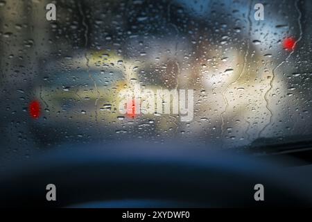 Blick auf ein Taxi durch die regengetränkte Windschutzscheibe eines Autos. Dämmerung Stockfoto