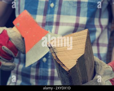 Junger Mann mit einer Axt und Feuerholz, selektiven Fokus auf Holz, Retro-Film stilisiert, alternative Energiekonzept Stockfoto